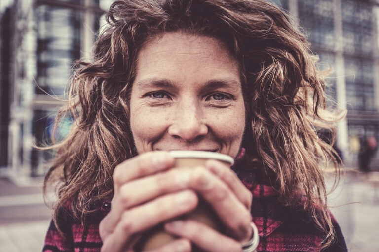 A woman holds a cup in front of her face while smile - we have used an istock photo to protect Emma's identity