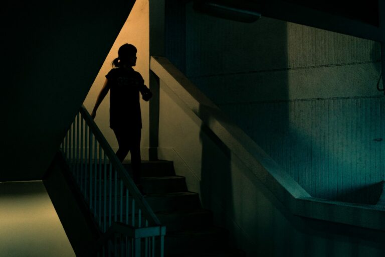 Silhouette of a woman walking down some steps to leave a building