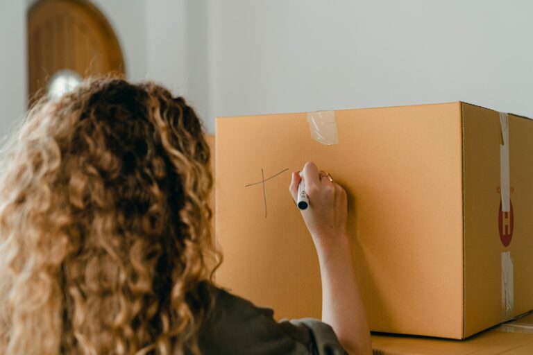 Woman writing label on a box as if she is moving home