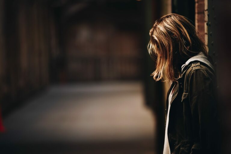 Homeless woman stood against wall