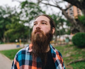 Bearded man in flannel shirt looking pensive